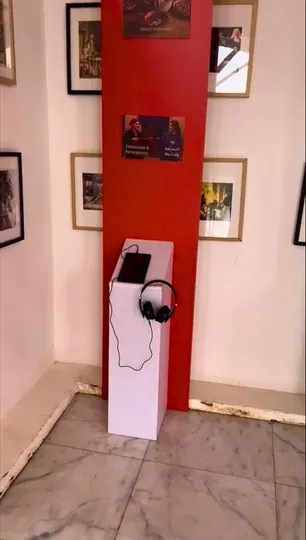 Red panel with a white listening station and headphones in front.