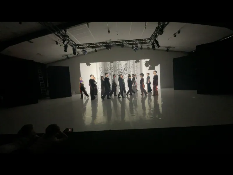 Dark stage with a row of performers in front of a projected image.