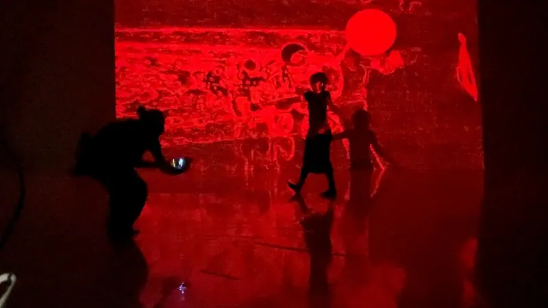 Figures moving in a room bathed in red projected light.