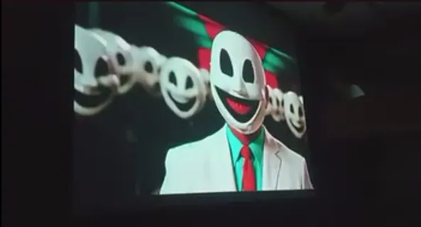 Projected frame of a figure in a white suit with a cartoon smiling mask.