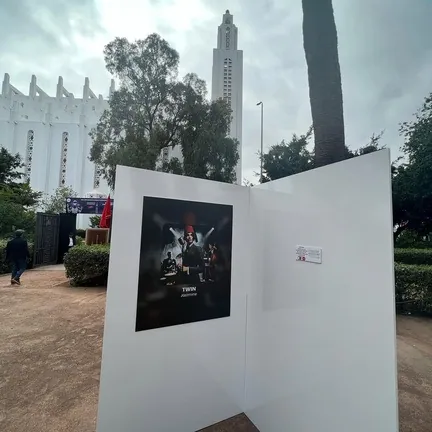 White outdoor display panel with an AI painting, a tall white tower behind it.