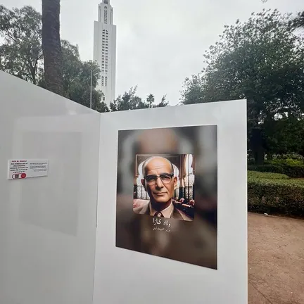 Outdoor panel with an AI portrait of an older man, trees and a tower in the background.